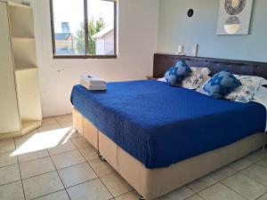 Hotel Mar Sur في تالكاهوانو: غرفة نوم بسرير وملاءات زرقاء ونافذة