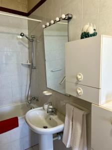uma casa de banho com um lavatório, um espelho e uma banheira em Appartamento con accesso privato spiaggia em Savona