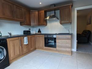 a kitchen with wooden cabinets and a stove top oven at Greystone holiday lets in Greyabbey