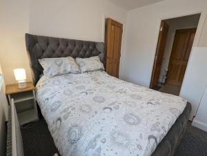 1 dormitorio con 1 cama grande y cabecero gris en Greystone holiday lets, en Greyabbey