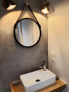 La salle de bains est pourvue d'un lavabo blanc et d'un miroir. dans l'établissement Sur le Port de Plaisance - Anatoline Appart'Hotel, à Audierne