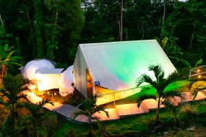 un grand bâtiment avec un toit en étain dans une forêt dans l'établissement HOTEL, VILLAS y GLAMPINGS MYA -PUERTO VIEJO, Limon, CR, à Puerto Viejo