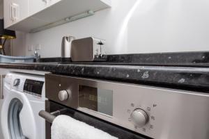 a kitchen with a washing machine and a sink at Flat 5- Cozy Studio Flat in The Heart of Crawley in Crawley