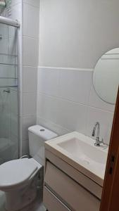 a bathroom with a toilet and a sink and a mirror at Apto inteiro - WiFi, ar condicionado, Piscina in Cuiabá