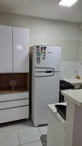 a kitchen with a white refrigerator and white cabinets at Apto inteiro - WiFi, ar condicionado, Piscina in Cuiabá