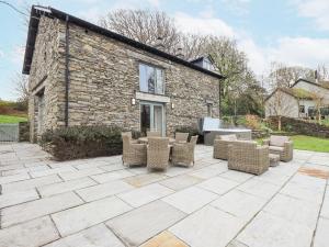 eine Terrasse mit Stühlen und ein Steingebäude in der Unterkunft Keepers Cottage in Ulverston