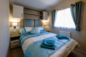 Porchfield的住宿－10 Beachlands，一间卧室配有一张带蓝色床单的床和一扇窗户。