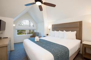 a bedroom with a large bed with a ceiling fan at Wave Crest Resort in San Diego