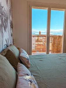 - un lit avec des oreillers dans une chambre avec une fenêtre dans l'établissement Le Panoramique - T2 46m² - Proche centre-ville et gare, à Perpignan