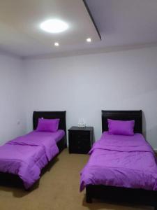 two beds in a room with purple sheets at Hanan petra House 