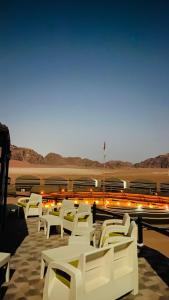 a group of white chairs sitting on a patio at Wadi Rum Majestic Camp in Wadi Rum