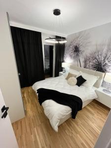 a bedroom with a large white bed with black and white pillows at Apartamenty Cieszyn in Cieszyn