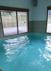 uma grande piscina de água azul num quarto com uma janela em Cosy du Birdie Logement 4 pers avec piscine em Giez