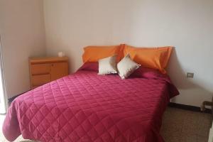 a bed with a red comforter and two pillows at IRIS Bilocale Sant'Anna in Busto Arsizio