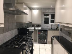 uma cozinha com um fogão e uma máquina de lavar roupa em Private room renovated with standard size brown desk in SE9 6PG em Londres