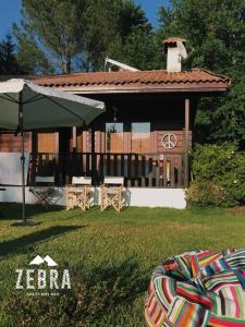 a house with a green umbrella in the grass at Zebra Country Wood House in Arcos de Valdevez
