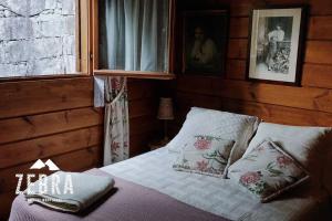una camera da letto con letto, cuscini e finestra di Zebra Country Wood House a Arcos de Valdevez