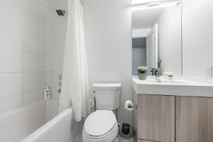 a white bathroom with a toilet and a sink at Jarvis Apartment in Toronto