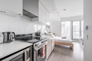 a white kitchen with a stove and a sink at Jarvis Apartment in Toronto