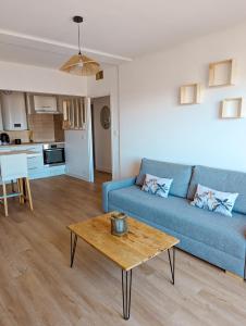 ein Wohnzimmer mit einem blauen Sofa und einem Couchtisch in der Unterkunft Le Panoramique - T2 46m² - Proche centre-ville et gare in Perpignan