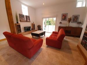 a living room with two red chairs and a television at Gite de la grange 14 couchages in Saint-Amand-Montrond