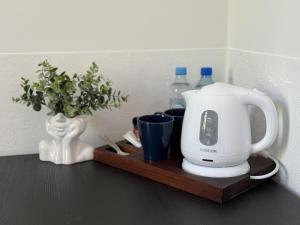 Una cafetera en una bandeja de madera con botellas de agua. en IRIS Aparthotel, en Cracovia