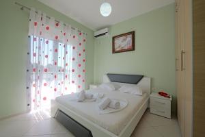 a bedroom with a bed with white sheets and a window at Villa e Olsi Kacupaj in Sarandë