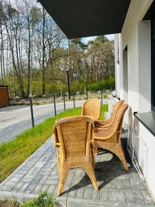 dos sillas de mimbre y una mesa en un porche en Apartamenty Dębowa 1 PRIV OGRÓD Z MIEJSCEM NA ROWERY, en Milicz