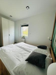 um quarto com uma grande cama branca e 2 almofadas em Apartamenty Dębowa 1 PRIV OGRÓD Z MIEJSCEM NA ROWERY em Milicz
