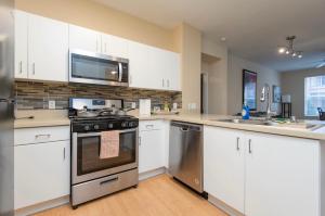 a kitchen with white cabinets and a stove top oven at spacious two bedroom 2 bath close to Disney Adventure Park in Anaheim
