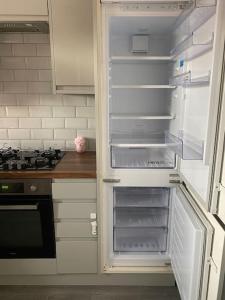an empty refrigerator with its door open in a kitchen at Brighton NEW Apartment FREE PARKING sleeps 6 in Brighton & Hove