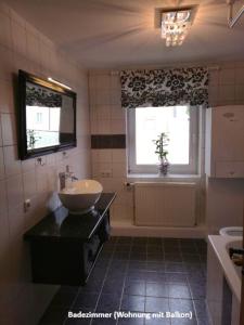 a bathroom with a sink and a tub and a window at Ferienwohnungen zentral Altötting in Altötting