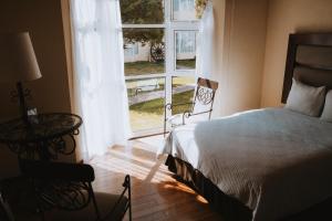 a bedroom with a bed and a large window at Hoteles Villa Mercedes San Cristobal in San Cristóbal de Las Casas