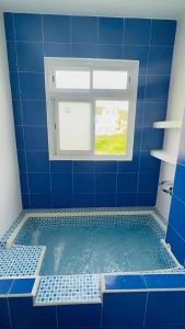 een blauw betegelde badkamer met een bad en een raam bij AzulRest Casa de Verano in Juan de Acosta