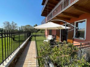 un balcón con sombrilla en una casa en Residence Albatros-Golf & Relax, en Toscolano Maderno