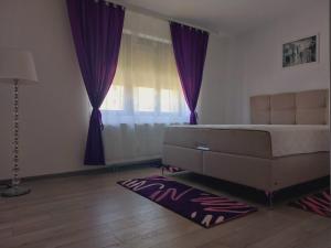 a bedroom with a bed with purple curtains and a rug at Apartmanii Gajić in Kuršumlija