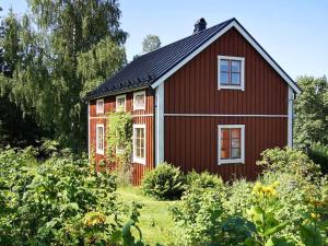 a red house with white windows in a garden at Holiday home NORDINGRÅ in Nordingrå