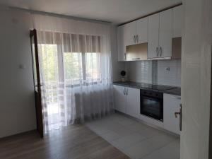 a kitchen with white cabinets and a window at Apartmanii Gajić in Kuršumlija