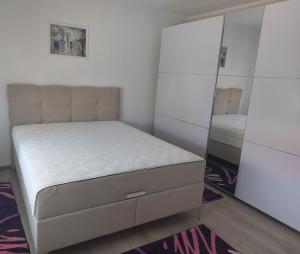 a small bedroom with a bed and a mirror at Apartmanii Gajić in Kuršumlija