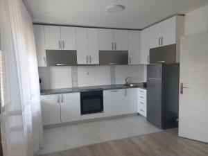 a kitchen with white cabinets and a black refrigerator at Apartmanii Gajić in Kuršumlija