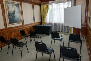 una sala de conferencias con sillas y una pantalla blanca en abba Presidente Suites Puerto Montt, en Puerto Montt