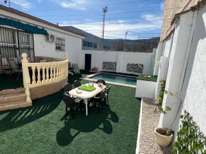un patio con mesa, sillas y piscina en Casa Rural Las Eras de Campotejar, 