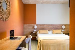 a bedroom with a bed and a desk with a laptop at Hostal Barris in Pals