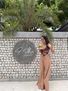 Omadhoo的住宿－Hitha Maldives，站在墙上喝着饮料的女人