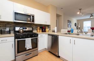 a kitchen with white cabinets and a stove and a sink at Two bedroom 2 bath close to Disneyland CA in Anaheim