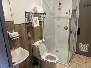 a bathroom with a shower and a toilet and a sink at Conway Motel Manukau in Auckland