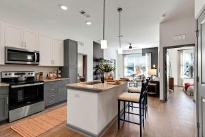 a kitchen with white cabinets and a island with bar stools at RISE Bartram Park Condos by Barsala in Jacksonville