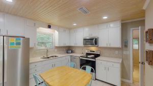 a kitchen with white cabinets and a wooden table at BEACHY SISTERS B Duplex in Jekyll Island