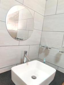 y baño con lavabo blanco y espejo. en Zulia home, en Pretoria