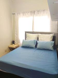 ein Bett mit blauer Bettwäsche in einem Schlafzimmer mit Fenster in der Unterkunft Zulia home in Pretoria
